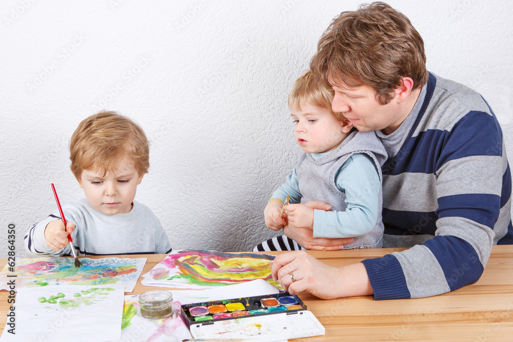 Father and two little boys siblings having fun painting Father and two little boys siblings having fun painting