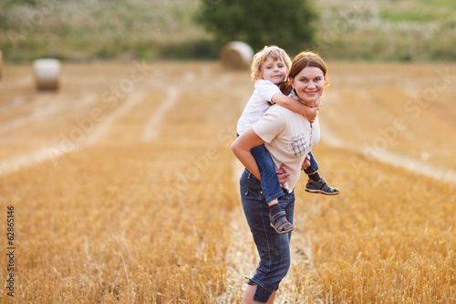 Young mother and her little son having fun on yellow hay field © Irina Schmidt