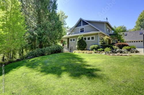 House with exotic flower bed, lawn and trees