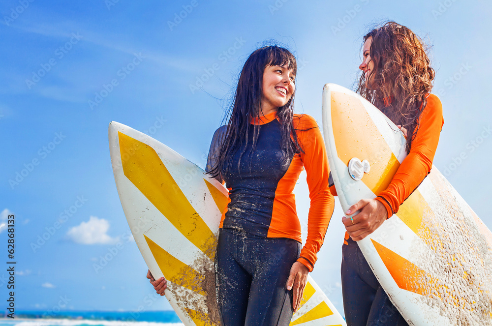 Obraz premium Surfer girls discussing something and smiling