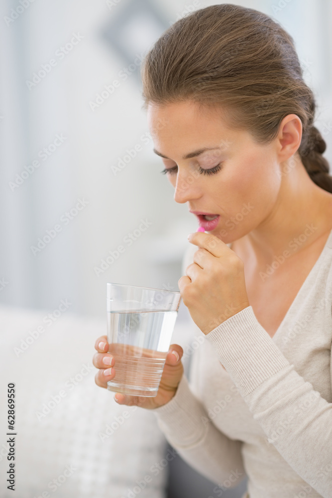 Portrait of young woman taking pill Portrait of young woman taking pill