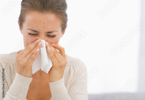 Portrait of young woman blowing nose photo