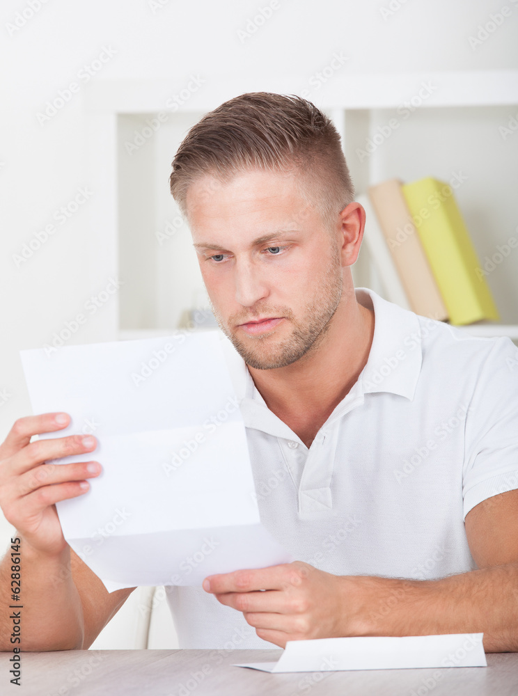 Man sitting reading a letter with a serious expression Man sitting reading a letter with a serious expression