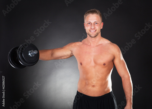 Muscular fit young man working out with weights