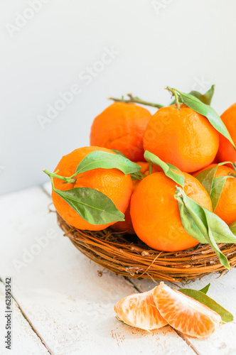 Tangerines in the basket on wooden background
