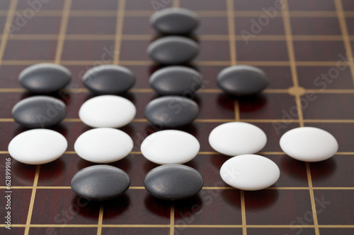 go game playing by stones on wood board