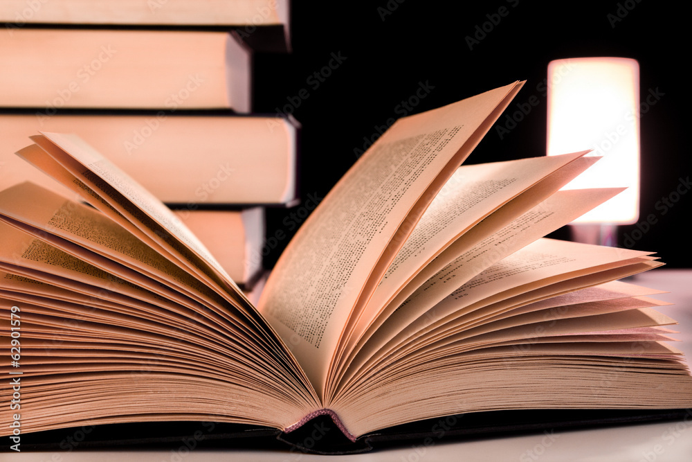 Fototapeta premium Buch aufgeschlagen vor Bücherstapel