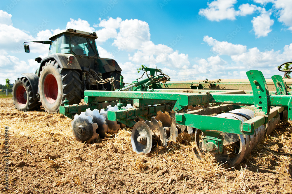 Obraz premium Ploughing tractor at field cultivation work