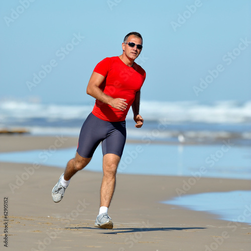 young man jogging on the beach in summer