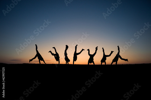 silhouetted gymnasts in sunset