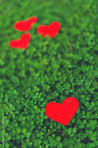 Red paper hearts in green clover