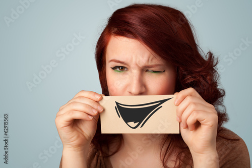 Happy cute girl holding paper with funny smiley drawing