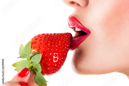 Fototapeta Seksowna kobieta ze zmysłowymi czerwonymi ustami je truskawkę na białym tle na ścianę
