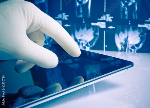 hand in glove touching modern digital tablet on x-ray images