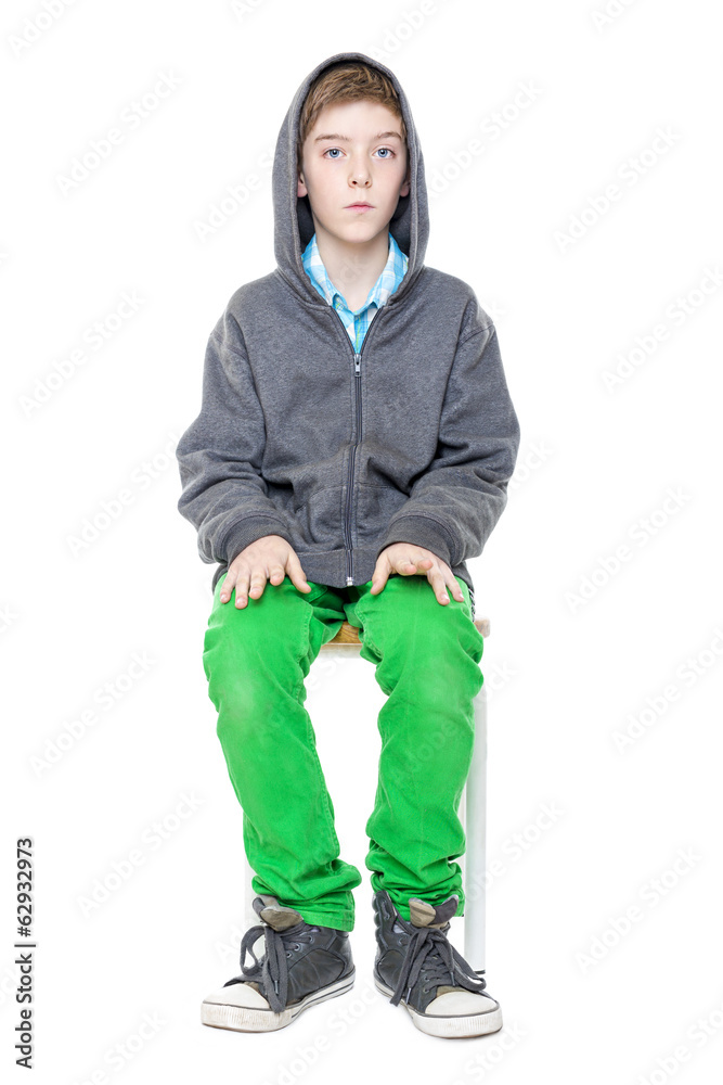 upright sitting male teenager on a stool, isolated on white