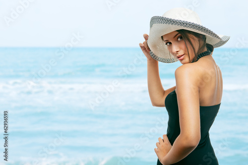 Pretty young woman holding her hat on her head