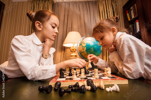 Closeup portrait of two little sisters playing chess