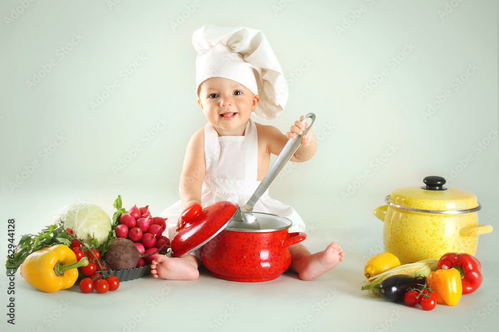 Baby wearing a chef hat with vegetables and pan Baby wearing a chef hat with vegetables and pan