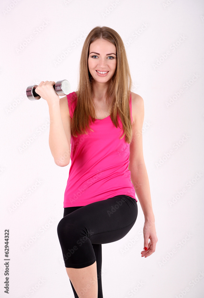 Young beautiful fitness girl exercising with dumbbells in gym Young beautiful fitness girl exercising with dumbbells in gym