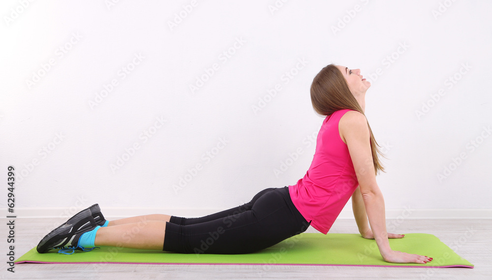 Young beautiful fitness girl exercising on green mat, in gym Young beautiful fitness girl exercising on green mat, in gym