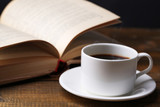 Cup of hot tea with book on table on gray background