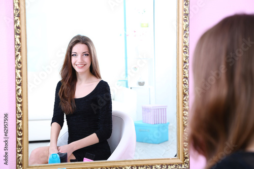 Young beautiful woman sitting front of mirror in room photo