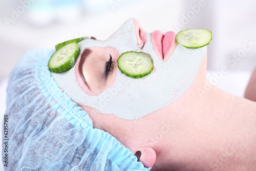 Young woman with clay facial mask in spa salon