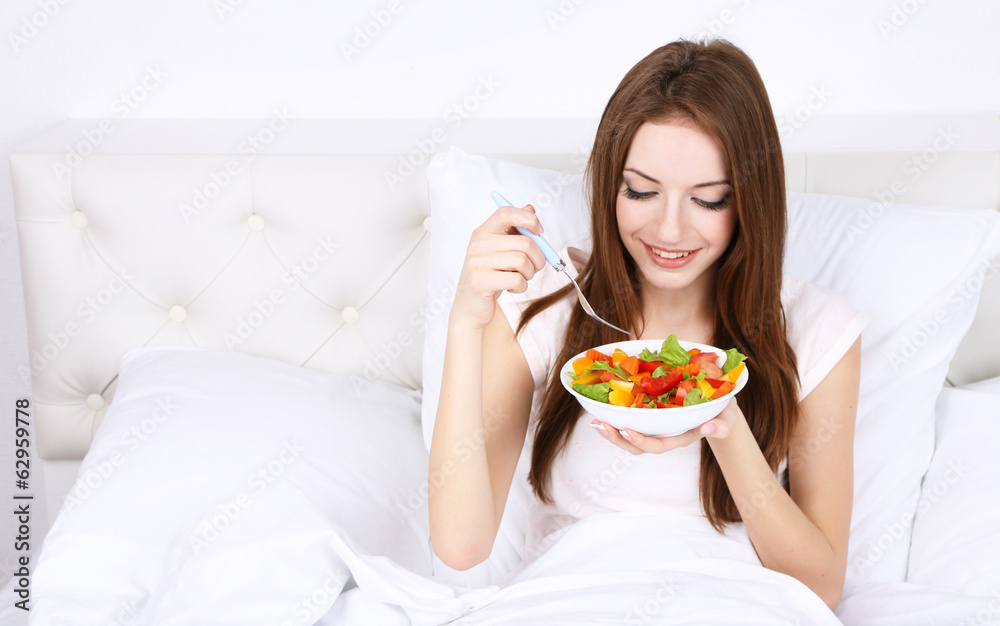 Young beautiful woman in bed with light breakfast