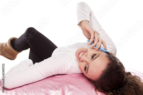 young girl lying on a large pillow and talking on the phone