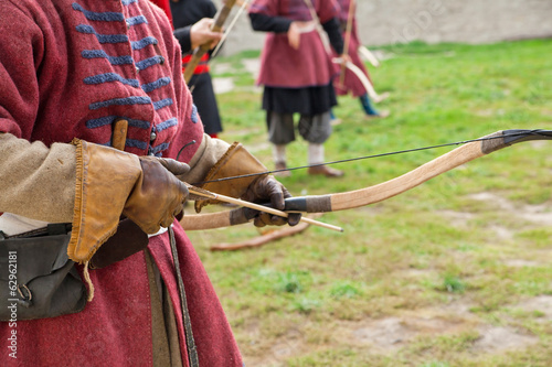 Archer with bow and arrows in medieval costume aiming,