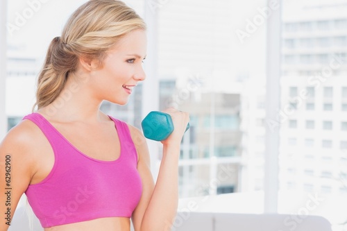 Pretty blonde lifting dumbbells and smiling