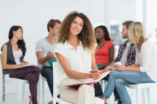 Smiling woman looking at camera while colleagues are talking