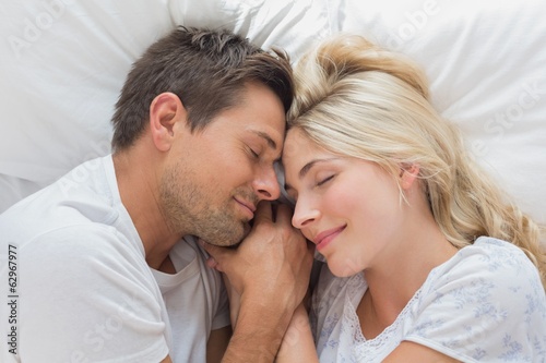 Loving couple lying in bed with eyes closed