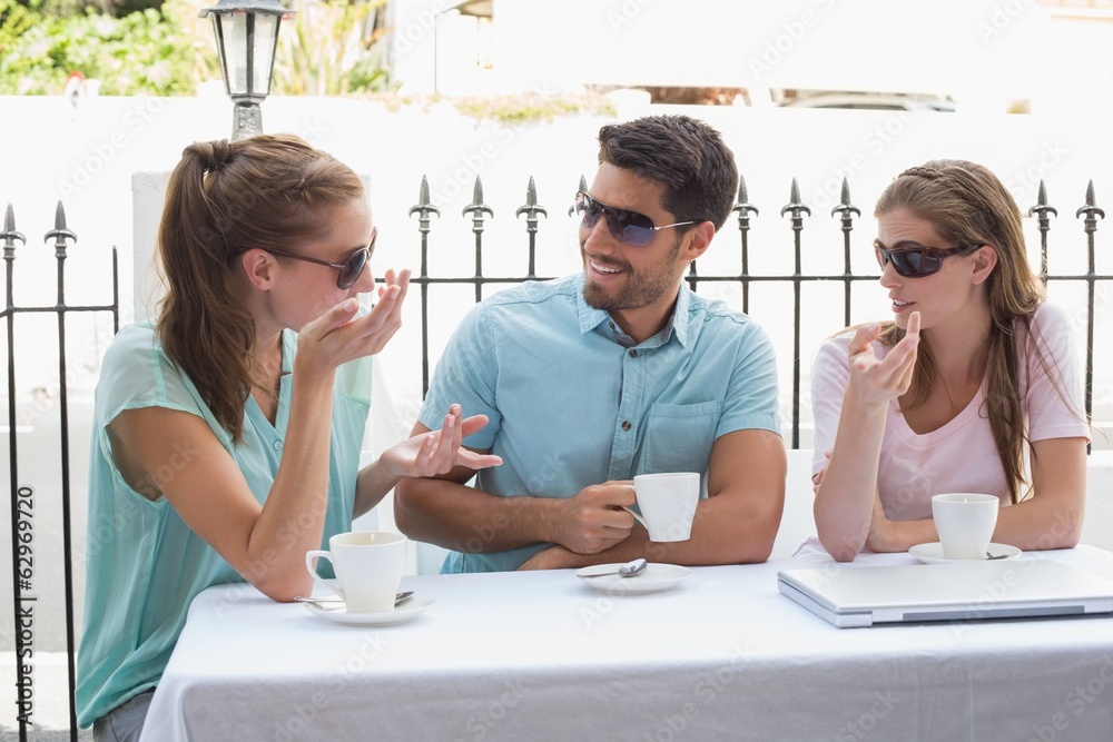Fototapeta premium Three happy friends having coffee in café