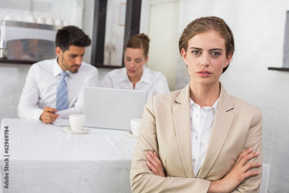 Confident businesswoman with colleagues at office desk Confident businesswoman with colleagues at office desk