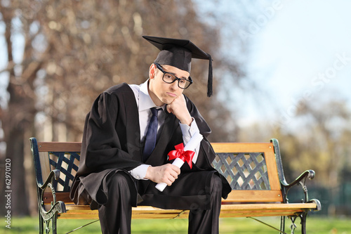 фотографія Sad college student sitting on a bench in park