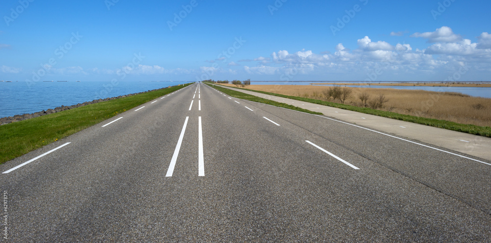 Road on a dike along a lake in spring