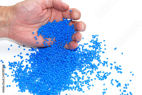 Hand schüttet blaues Granulat