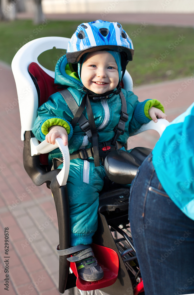 Naklejka premium Little boy in the seat bicycle behind mother