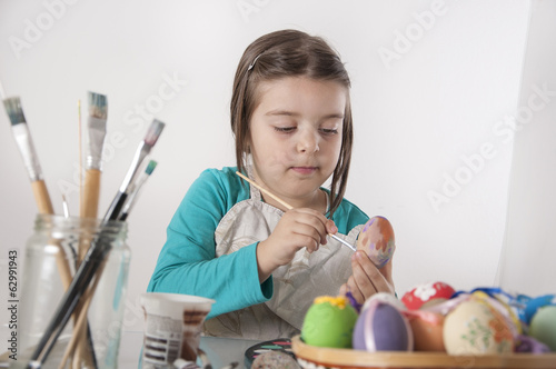 Little girl is painting eggs photo