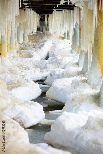 Winter. Baltic Sea. Ice formations icicles on pier poles #62993563