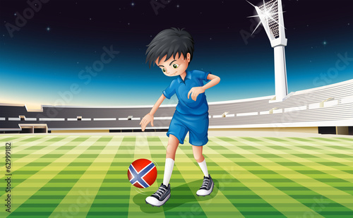 A boy at the field using the ball with the flag of Norway