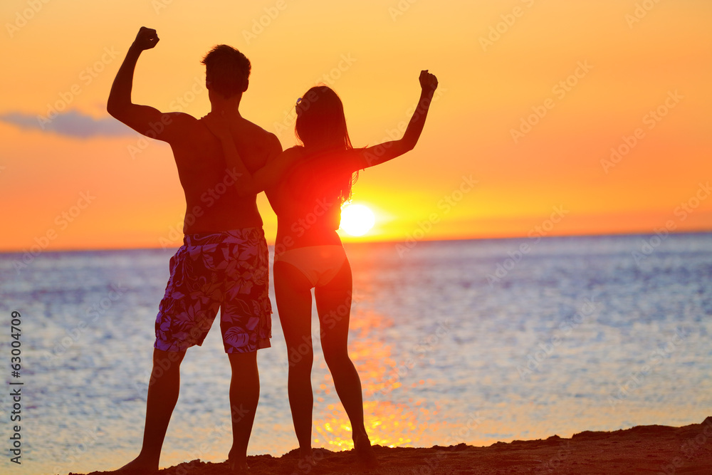 Sporty fitness couple cheering at beach sunset