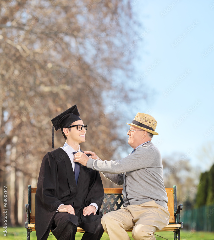 Graduate student and his proud father sitting in park