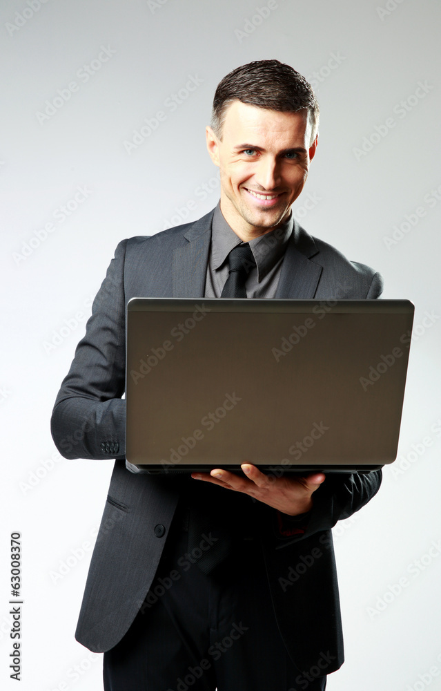 Happy businessman using laptop on gray background Happy businessman using laptop on gray background