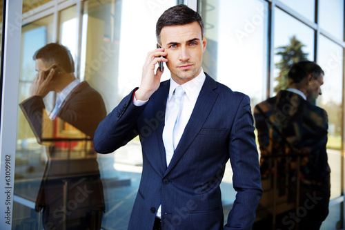 Confident businessman talking on the phone at office