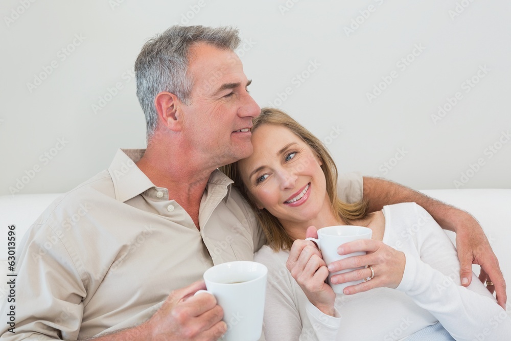Relaxed loving couple with coffee cups in living room Relaxed loving couple with coffee cups in living room