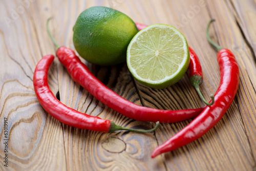 Close-up of limes and red chili peppers on a wooden surface