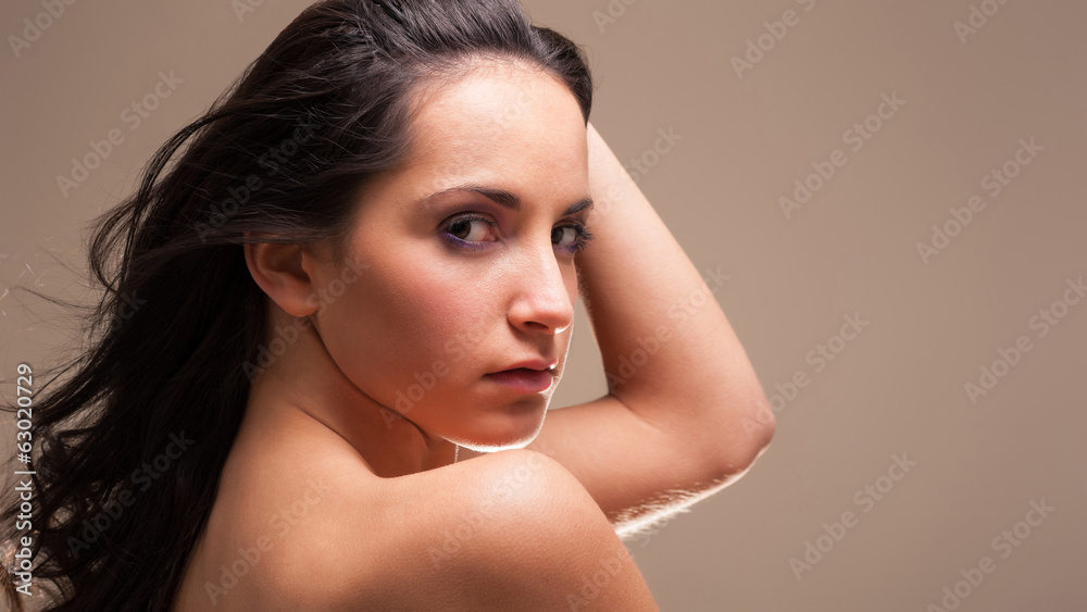Naklejka premium Young intimate brunette woman beauty portrait against brown back