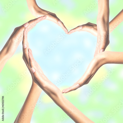 Human hands in heart shape over bright background